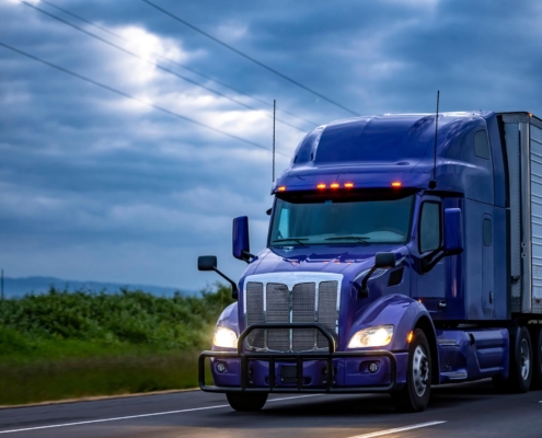 Side view of semi-truck driving down the road on a cloudy day