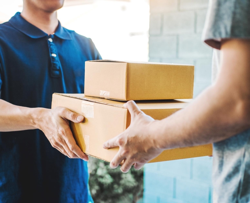 Side view of a deliveryman giving two small boxes to a customer