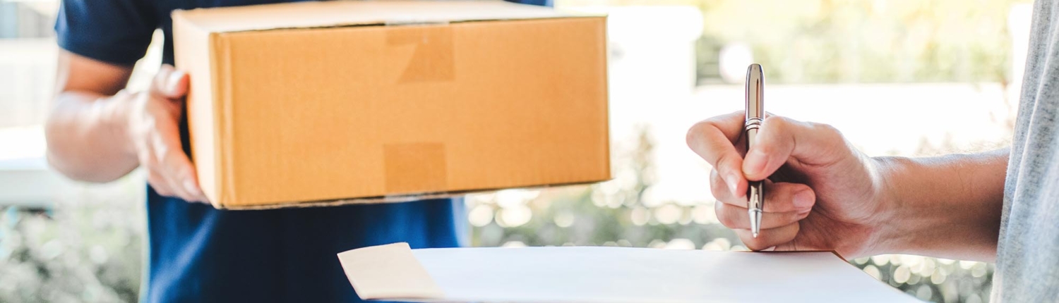 Side view of a man signing for a package with a deliveryman standing in the background