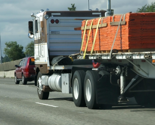 Semi truck with flatbed load driving down highway